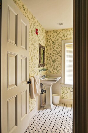 A bathroom with floral wallpaper, a white sink, and a tiled floor.