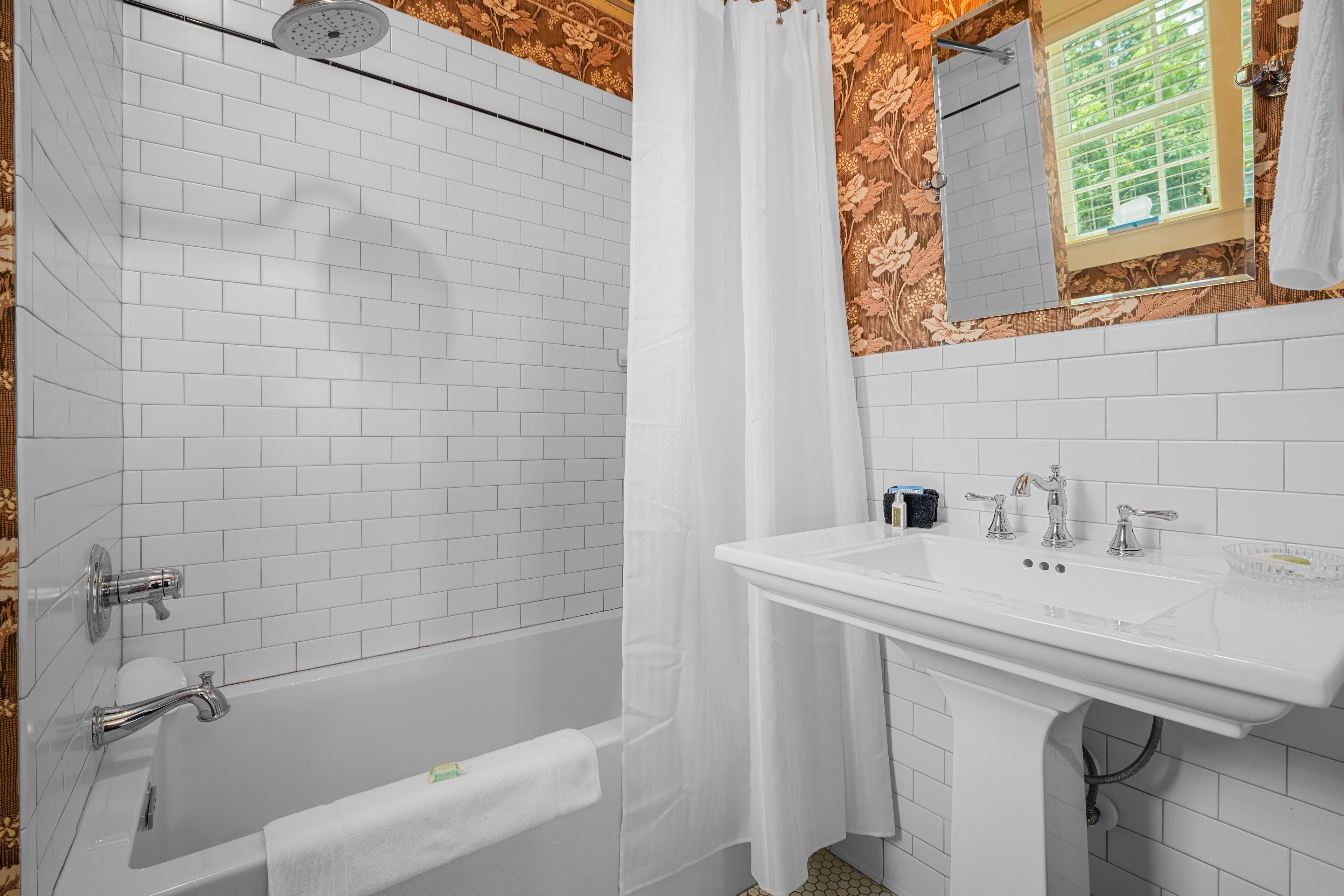 A bathroom with a white bathtub, a white sink, and a mirror above the sink.