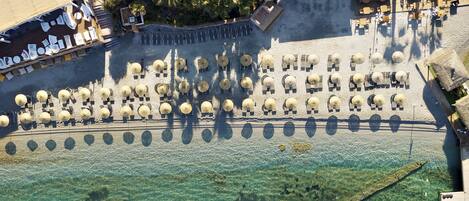 An aerial view of a resort with a swimming pool, sun loungers, and a beach area.