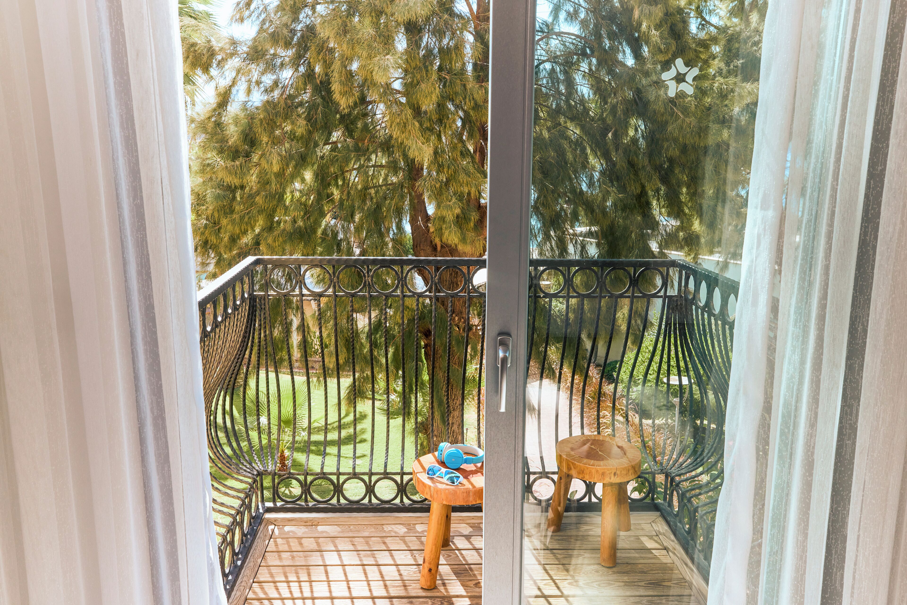 A balcony with a wrought iron railing, a small wooden table, and a chair.