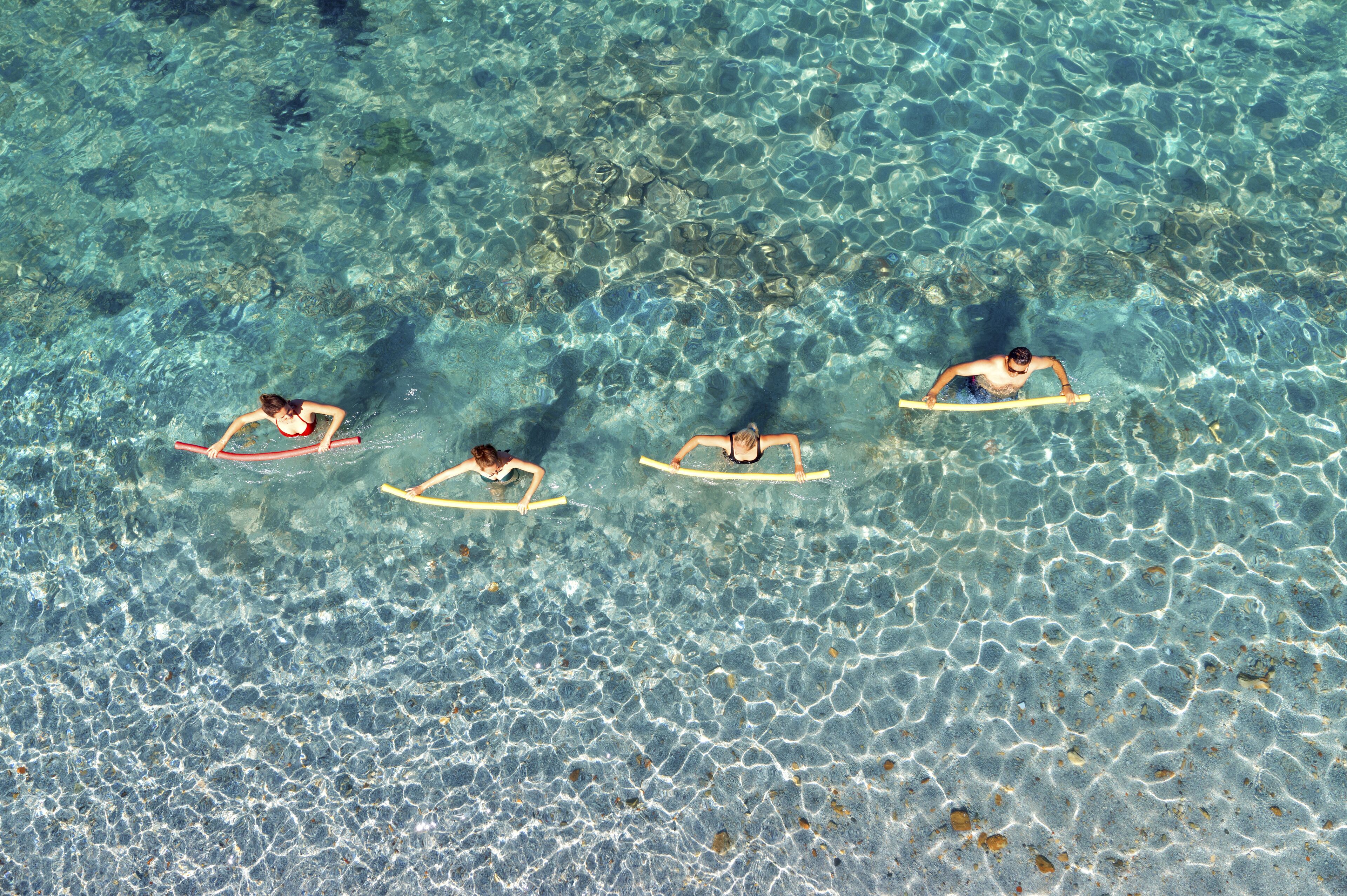 A clear view of a beach with three people on surfboards.