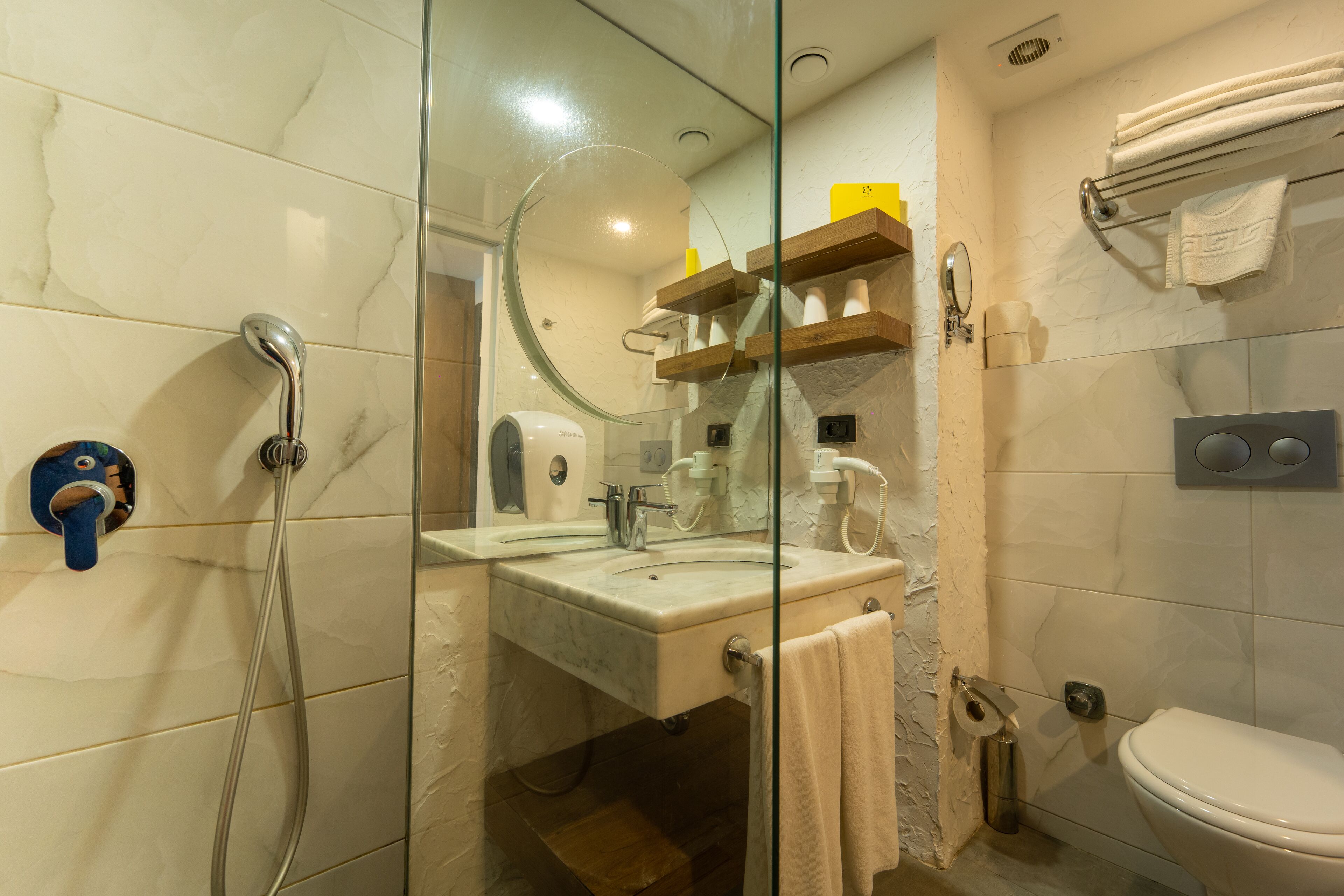 Une salle de bain avec une douche à parois de verre, un lavabo avec un miroir, des toilettes et un porte-serviettes.