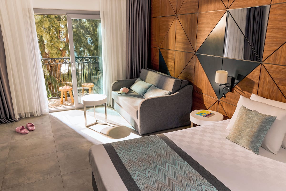Une chambre d’hôtel avec un lit, un canapé, une petite table et une vue sur l’extérieur.