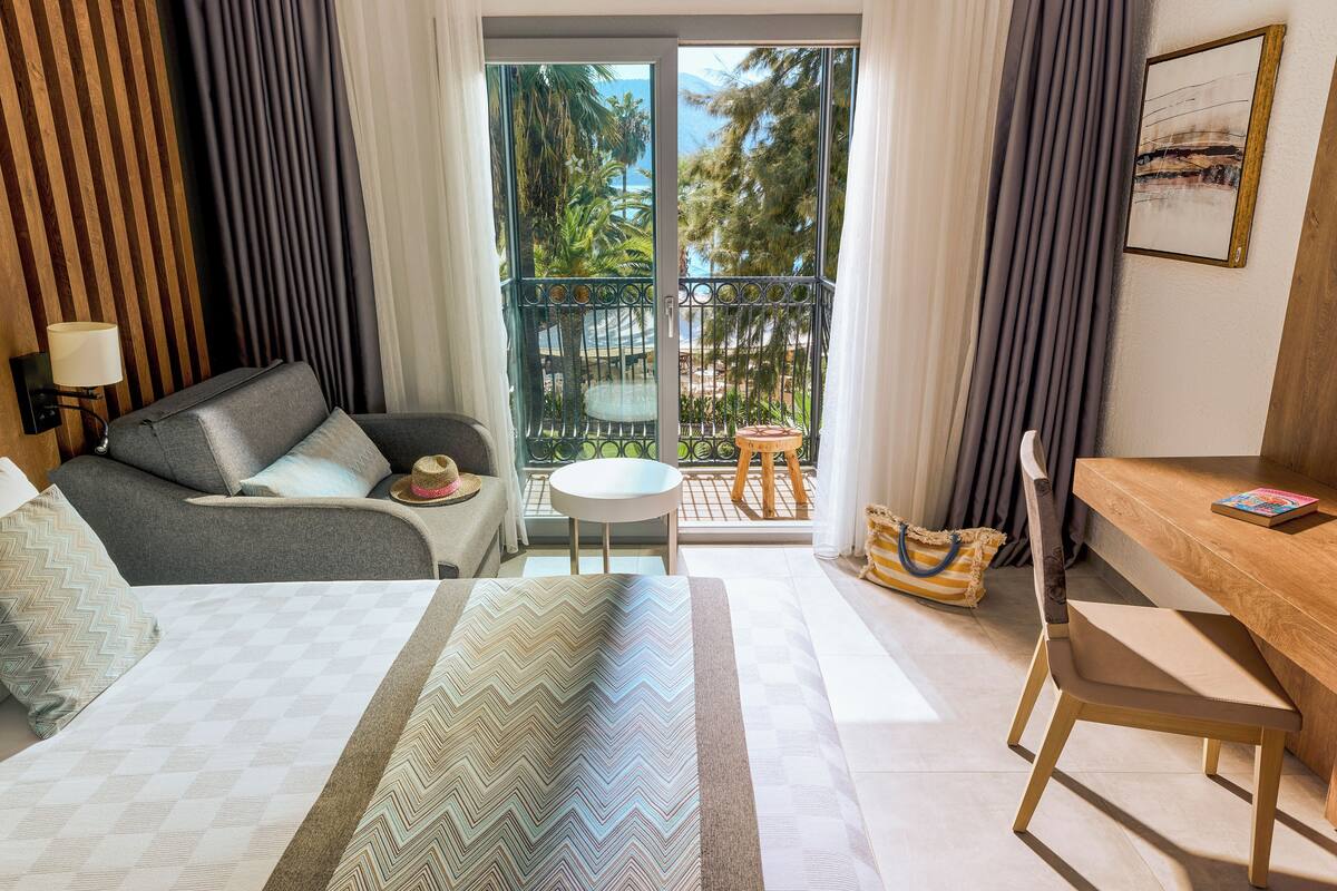 Une chambre d’hôtel comprenant un lit, un bureau, une chaise, une petite table et une vue sur l’extérieur.