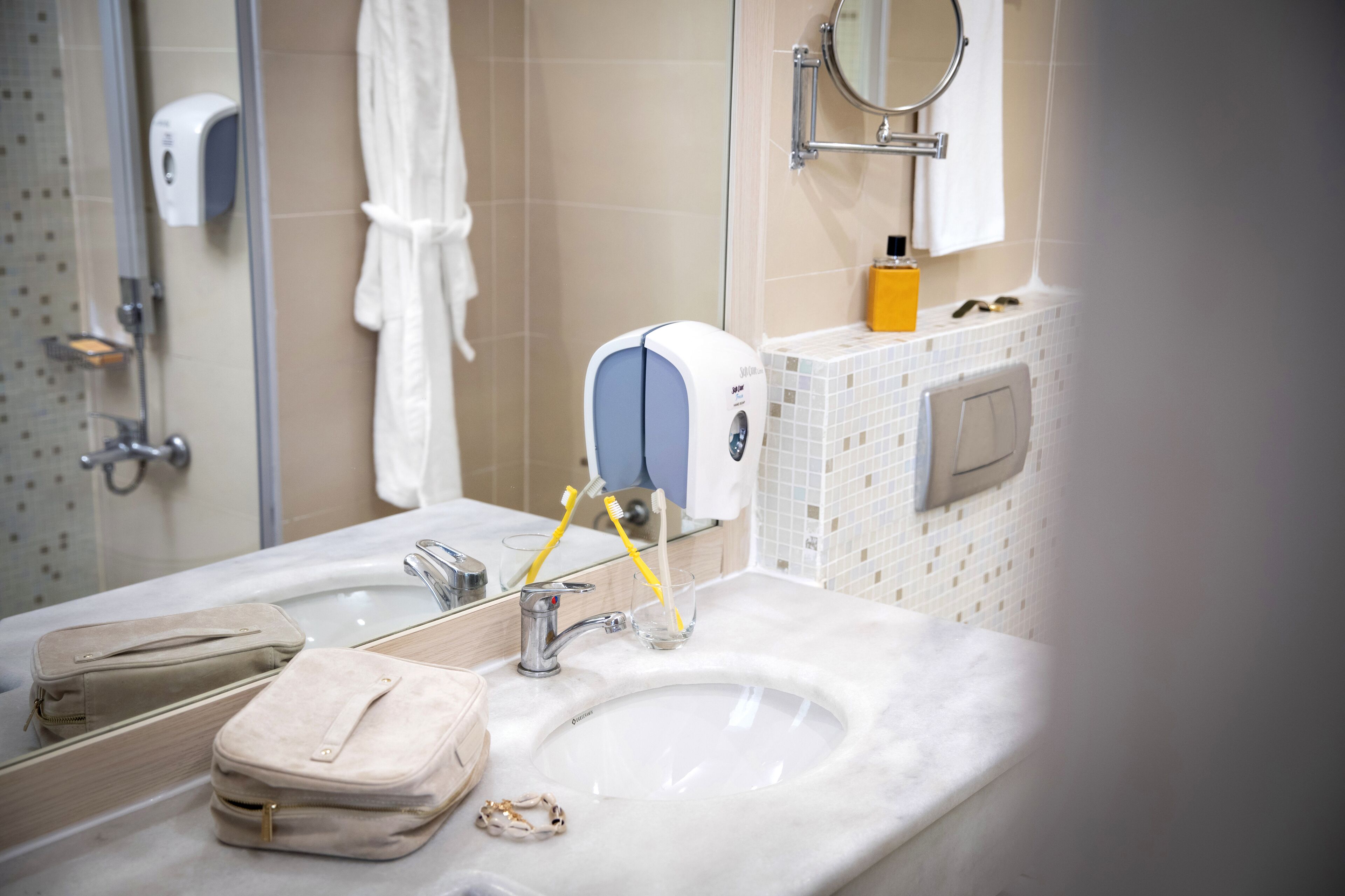 A bathroom with a sink, mirror, towel rack, and a hand dryer.