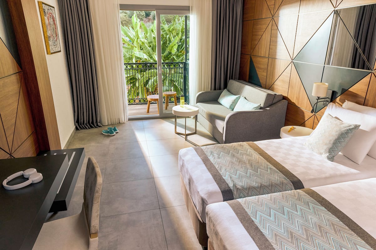 Une chambre d’hôtel comprenant un lit, un canapé, une petite table et un bureau avec un téléphone.