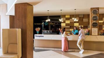 A reception area with a marble counter, wooden accents, and a modern chandelier.