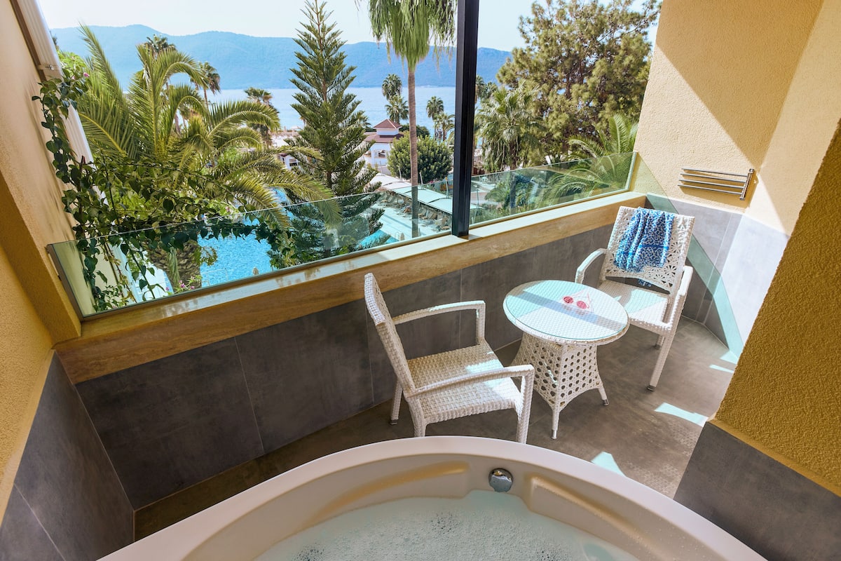 Un balcon avec vue sur la mer, un jacuzzi et des meubles en osier.