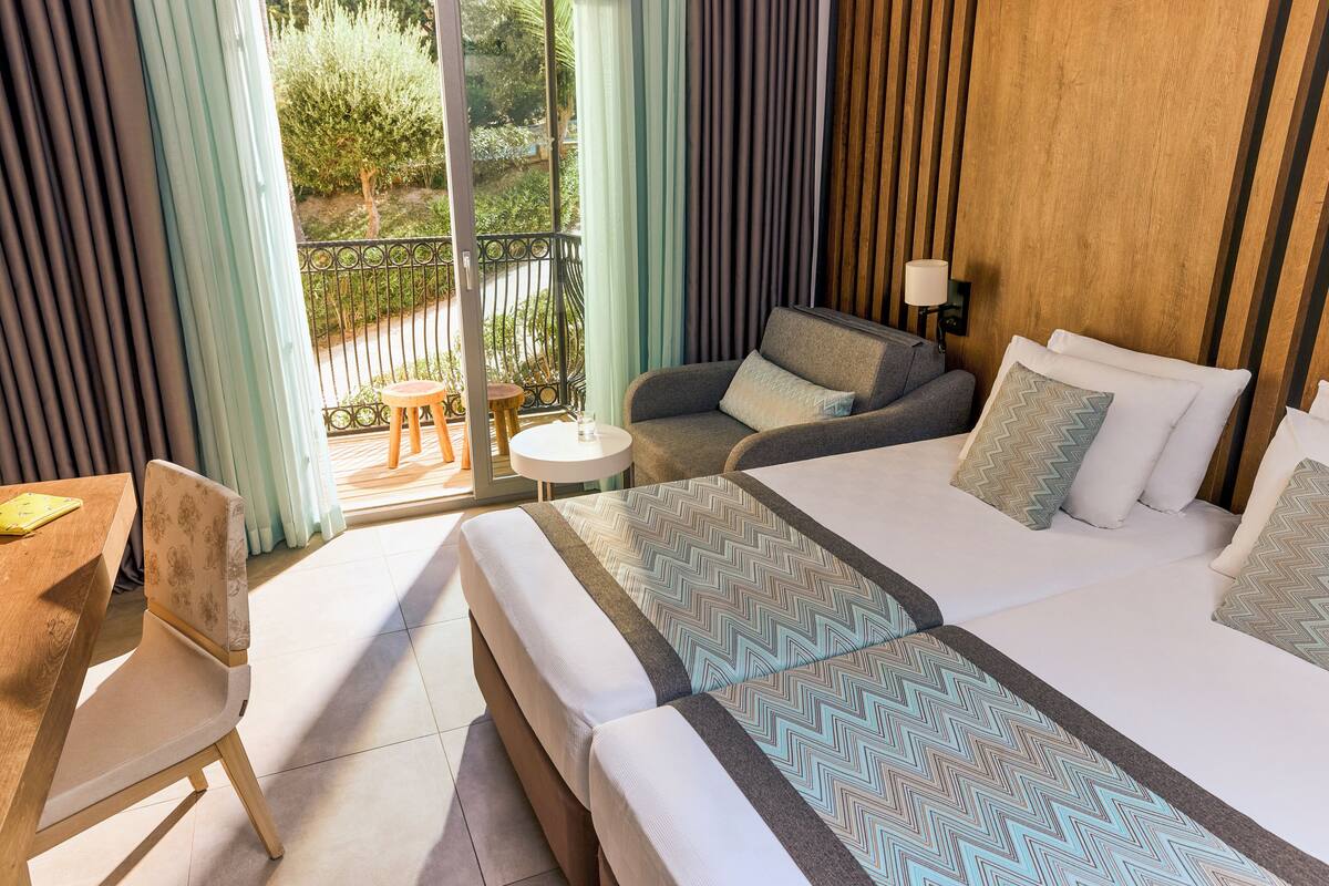 Une chambre d’hôtel avec un grand lit, deux canapés, une petite table et une chaise.