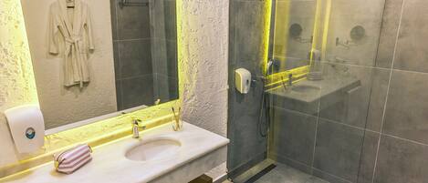A modern bathroom with a white sink, a glass shower enclosure, and a towel rack with a robe.