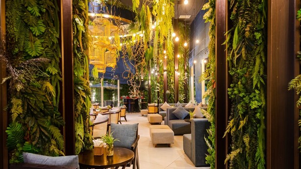A cozy indoor space with seating areas, a dining table, and lush green walls. - Muong Thanh Grand Ha Long Hotel (Bai Chay)