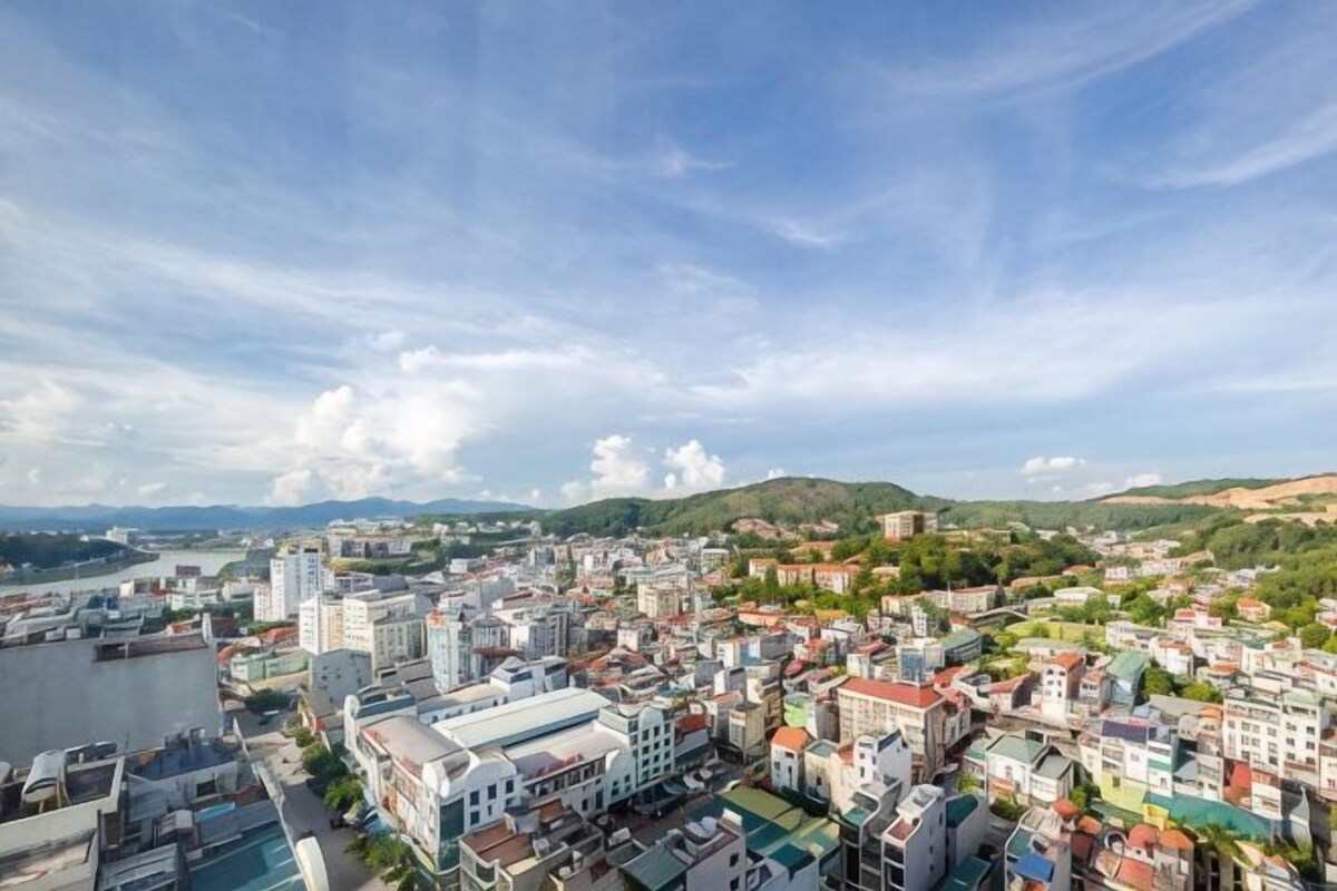 A cityscape with buildings, a river, and hills in the background.