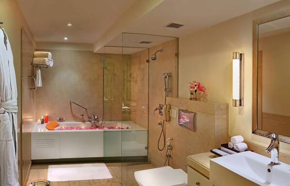 Un baño moderno con ducha envuelta en vidrio, una bañera grande, un tocador con lavabo y un espejo.