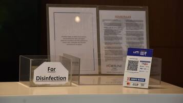 A display with a sign for disinfection, a document titled 'HOUSE RULES', and a QR code for payment at HDFC Bank.