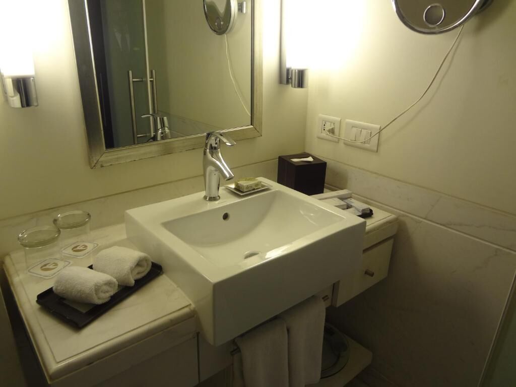 A bathroom with a white sink, mirror, and towel rack. There are two towels on the counter and a tissue box.