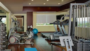 Une salle de sport équipée de tapis de course, de vélos d’exercice et de poids libres.