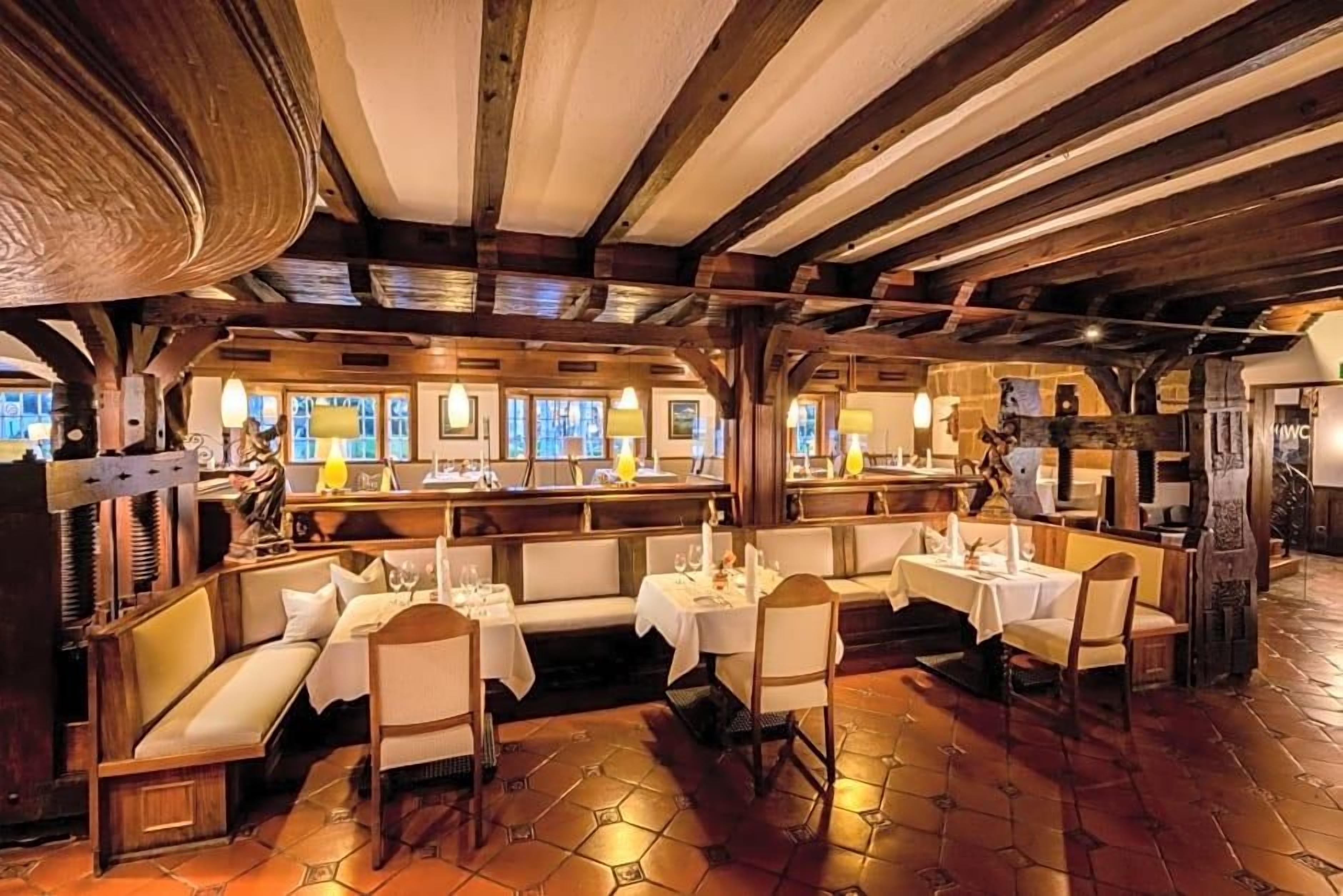 Ein Restaurant mit Holzbalken, weißen Sitzgelegenheiten mit Kissen und einem gefliesten Boden.