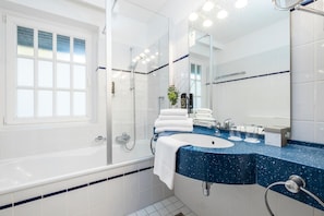 A modern bathroom with a bathtub, a sink, and a shower. - Carstens Landhaus (Timmendorfer Strand)