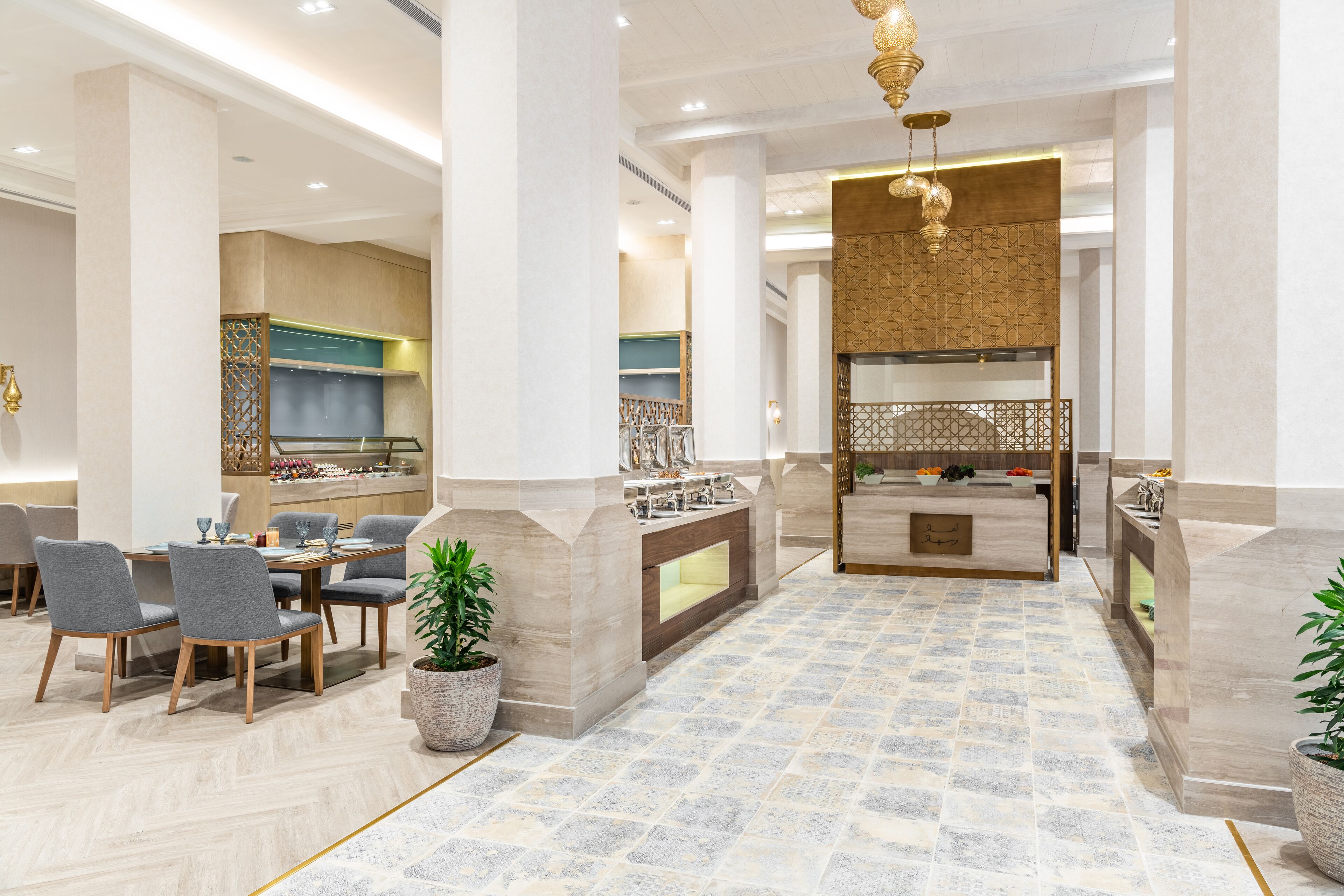 A modern hotel lobby with a central reception desk, seating area, and a decorative wall.