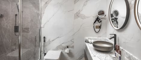 Ein modernes Badezimmer mit einer gläsernen Dusche, einer Toilette, einem Waschbecken mit großzügiger Spüle und zwei Wandspiegeln.