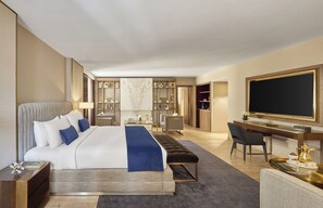 Habitación de hotel con una cama grande, un escritorio, una silla, un televisor y un minibar.