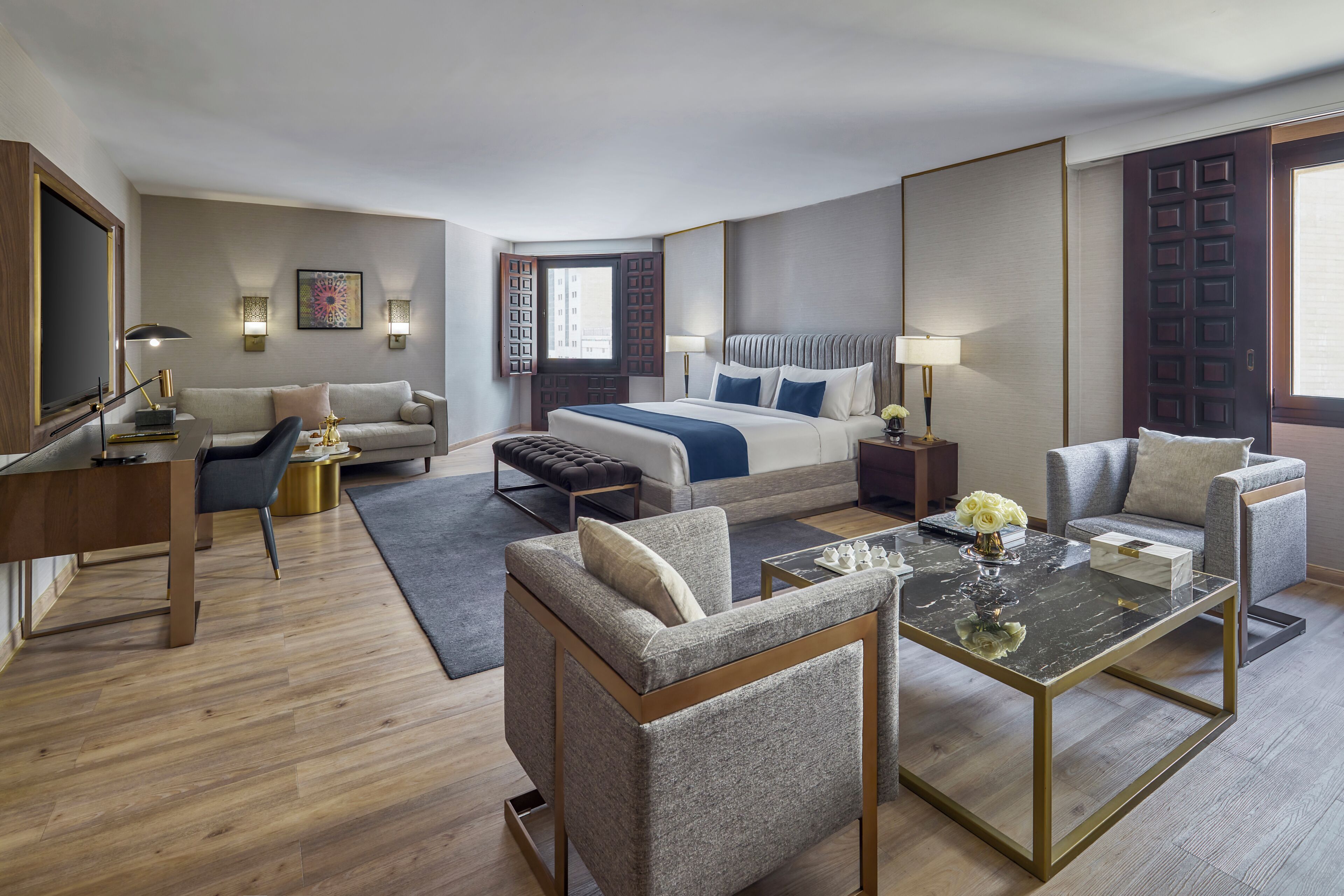 A hotel room with a bed, two armchairs, a sofa, a desk, and a coffee table.