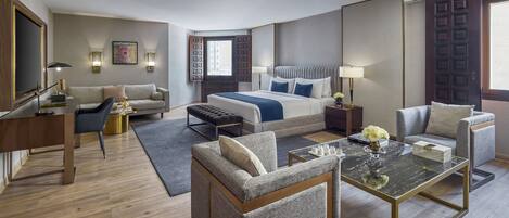 A hotel room with a bed, two armchairs, a sofa, a desk, and a coffee table.