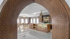Un hall d’hôtel moderne avec une arche en bois, un comptoir d’accueil et un espace détente comprenant des chaises et une table.