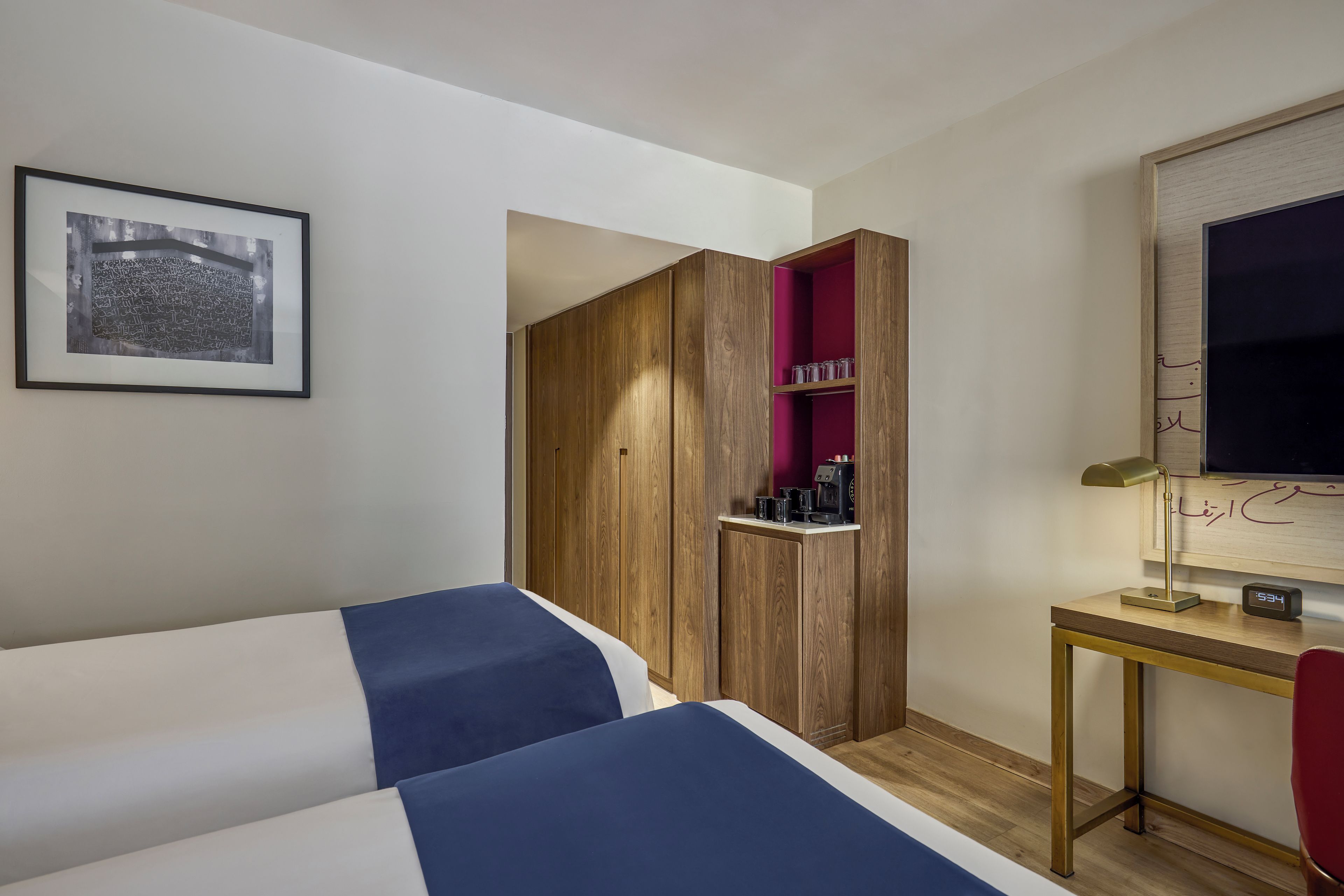 A hotel room with a bed, a desk, a TV, and a wardrobe.