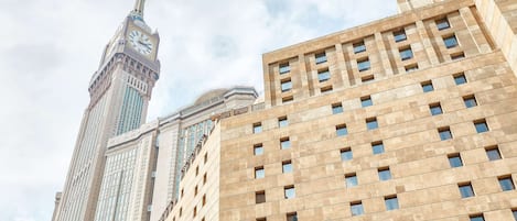 A high-rise building with a prominent clock tower and a modern structure with a grid-like facade.