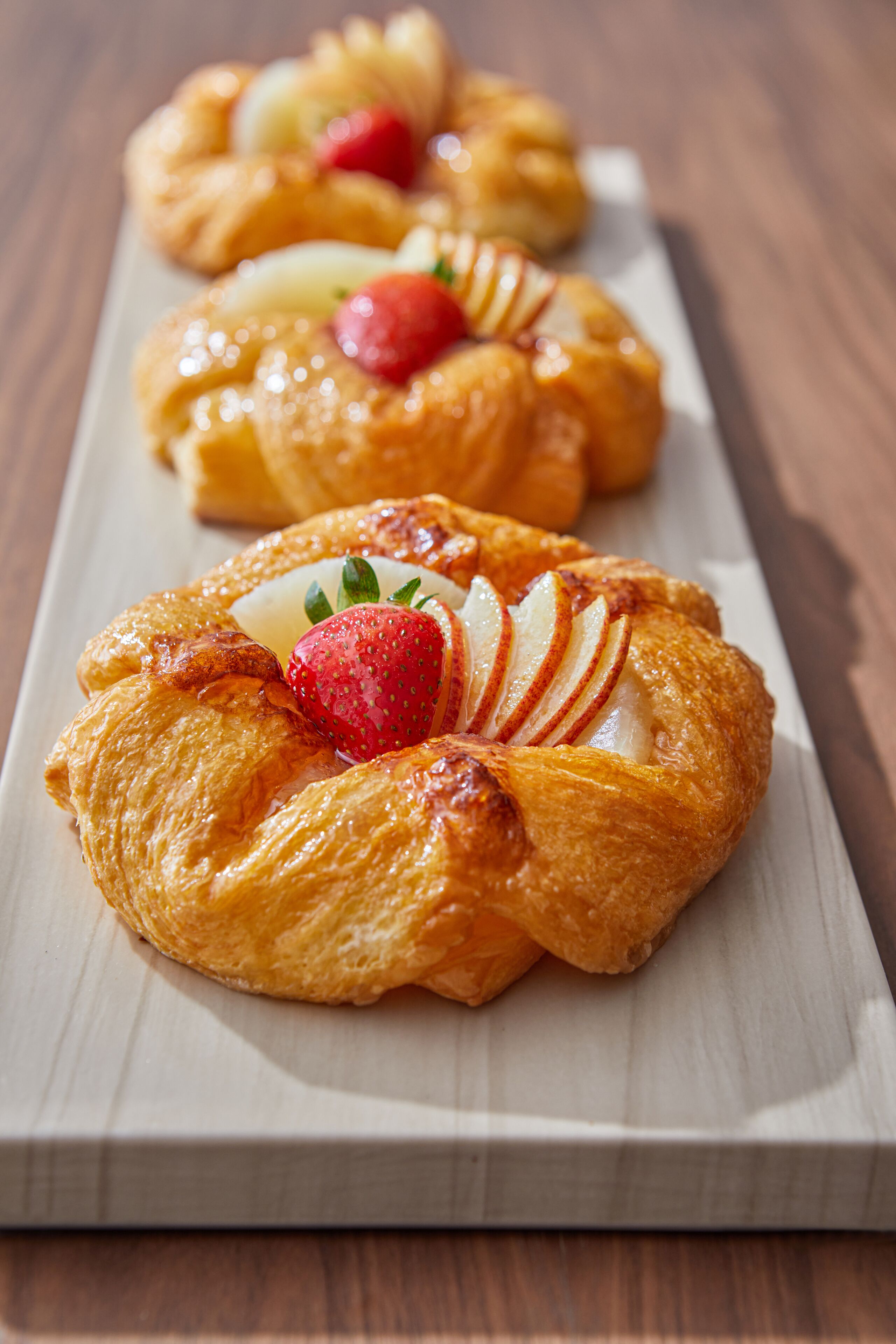 Three pastries on a wooden board.