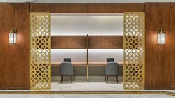 A room with two chairs facing a large window, wooden paneling, and decorative screens.