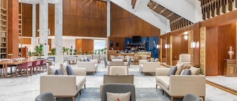 Eine großzügige Lobby mit mehreren Sitzbereichen, einem Empfangsbereich und einer Bar.