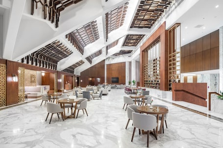 A spacious lobby with a high ceiling, marble flooring, and modern furniture.