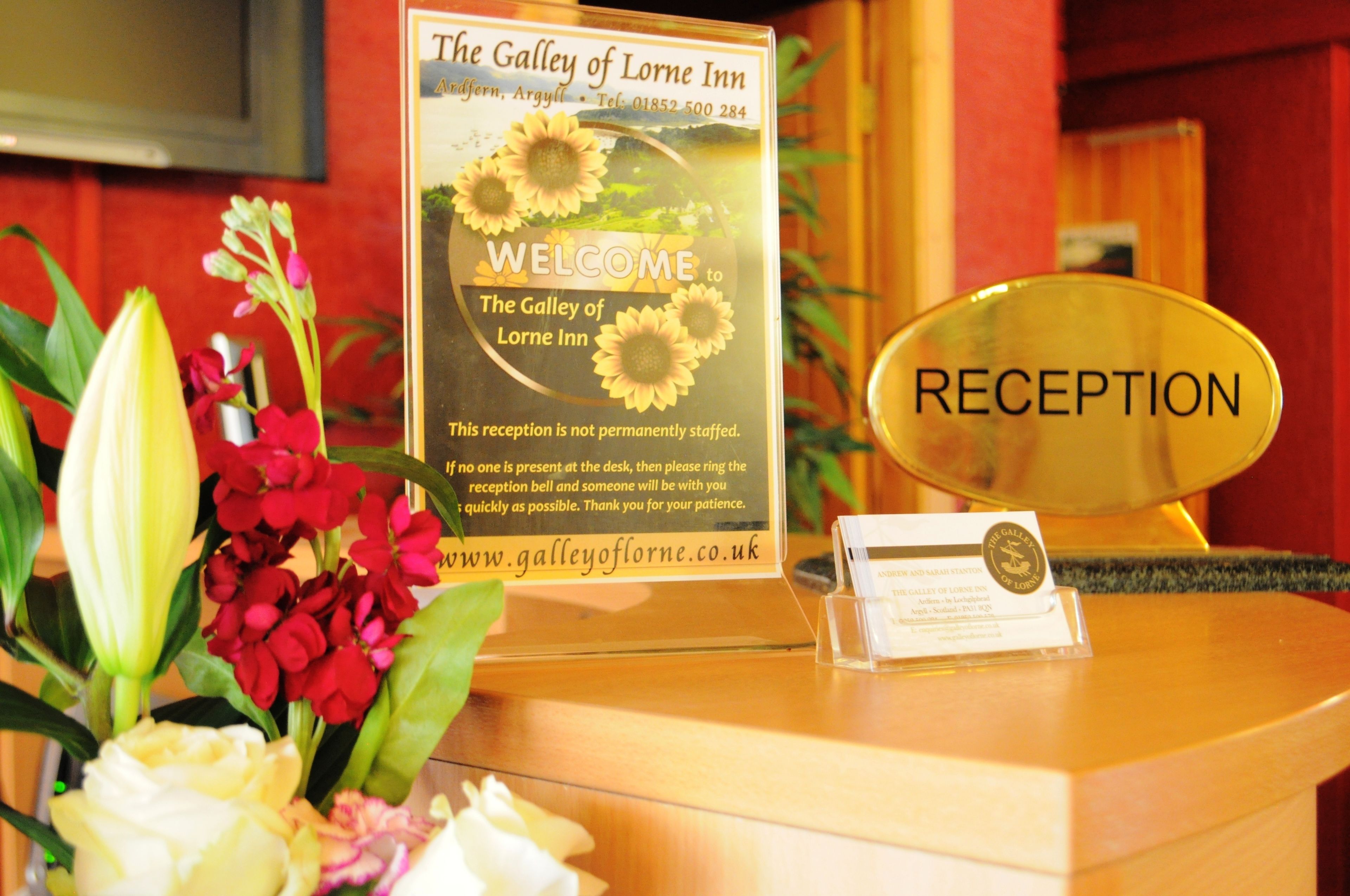 A reception desk at The Galley of Lorne Inn with a sign indicating it is not permanently staffed.