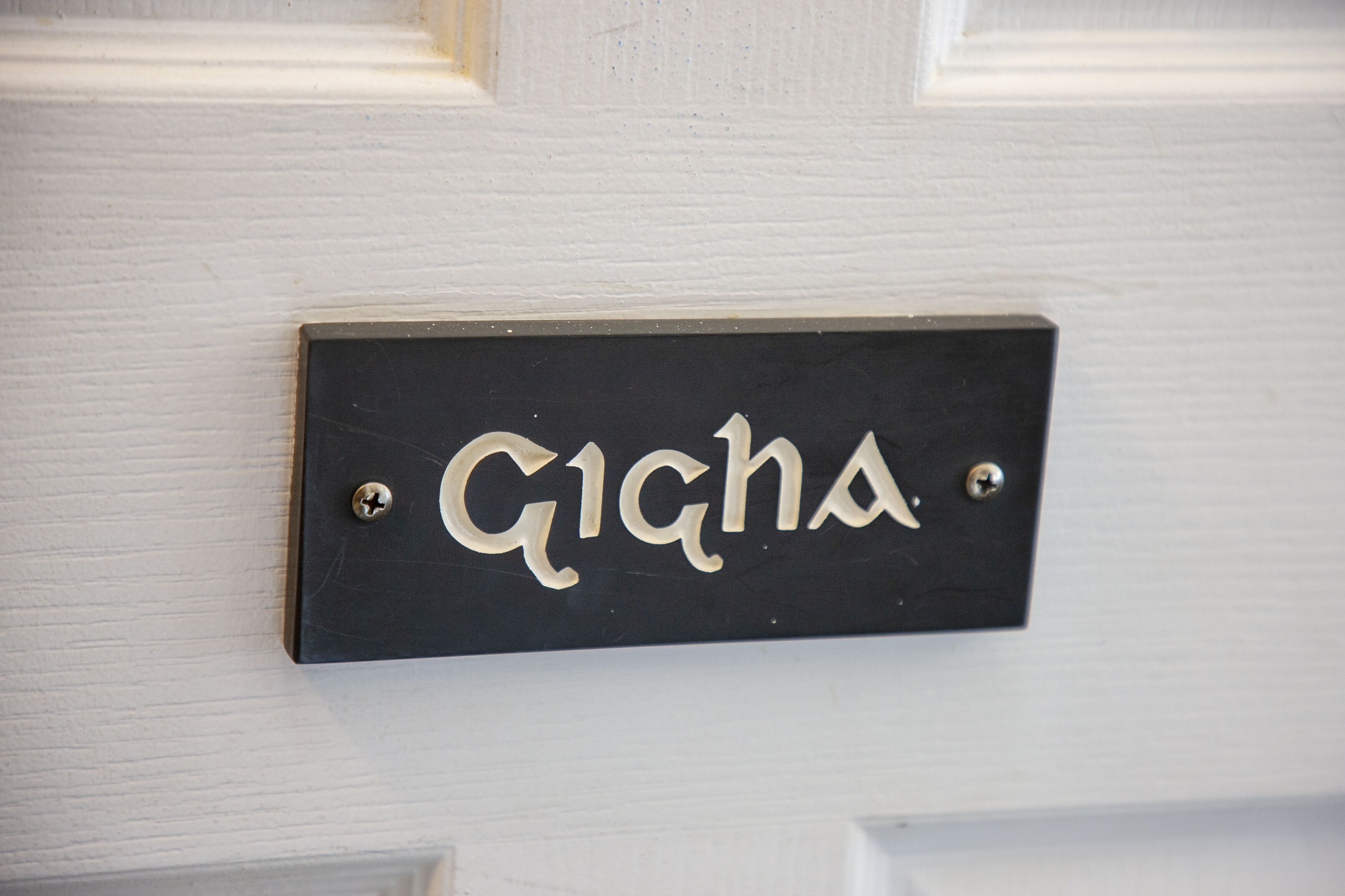 Una targa nera con il nome 'Gigha' fissata a una porta bianca.