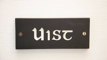 A black sign with white letters spelling "U1ST" mounted on a white wall.