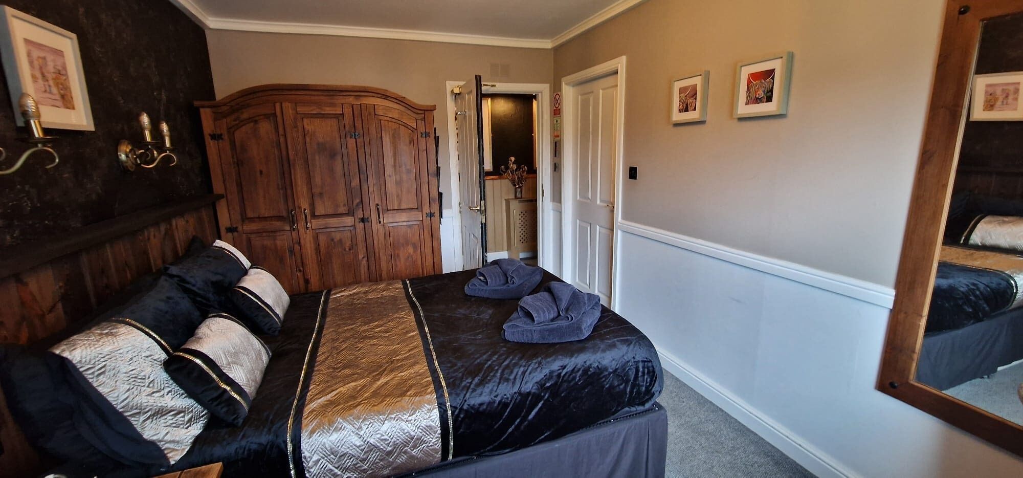 Un dormitorio con una cama grande, un armario de madera y un espejo.
