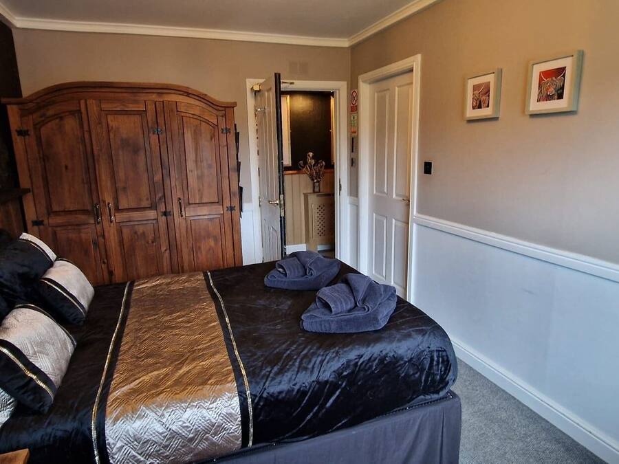 Un dormitorio con una cama grande, un armario de madera y un espejo.