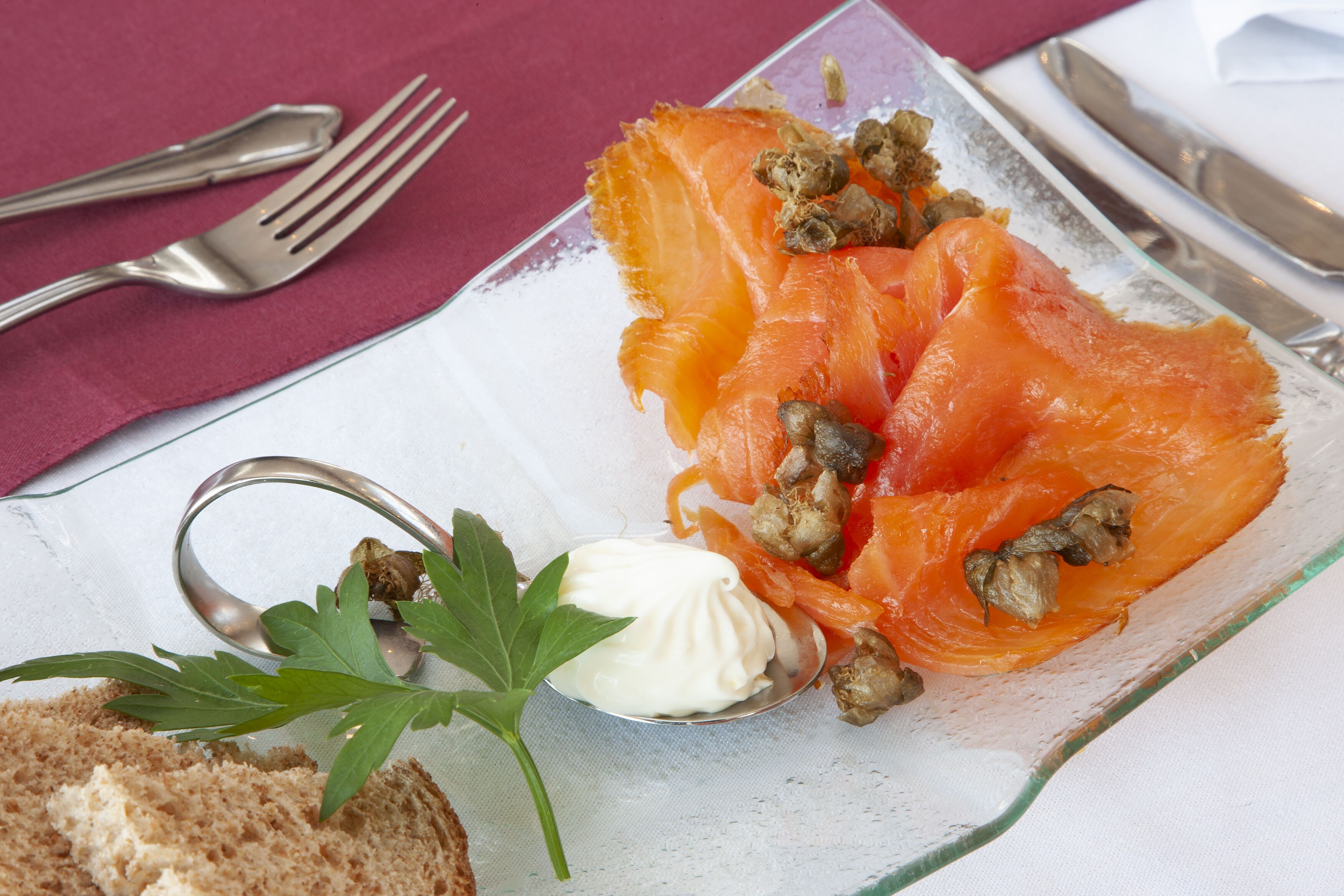 A glass plate with smoked salmon, mushrooms, and a dollop of cream.