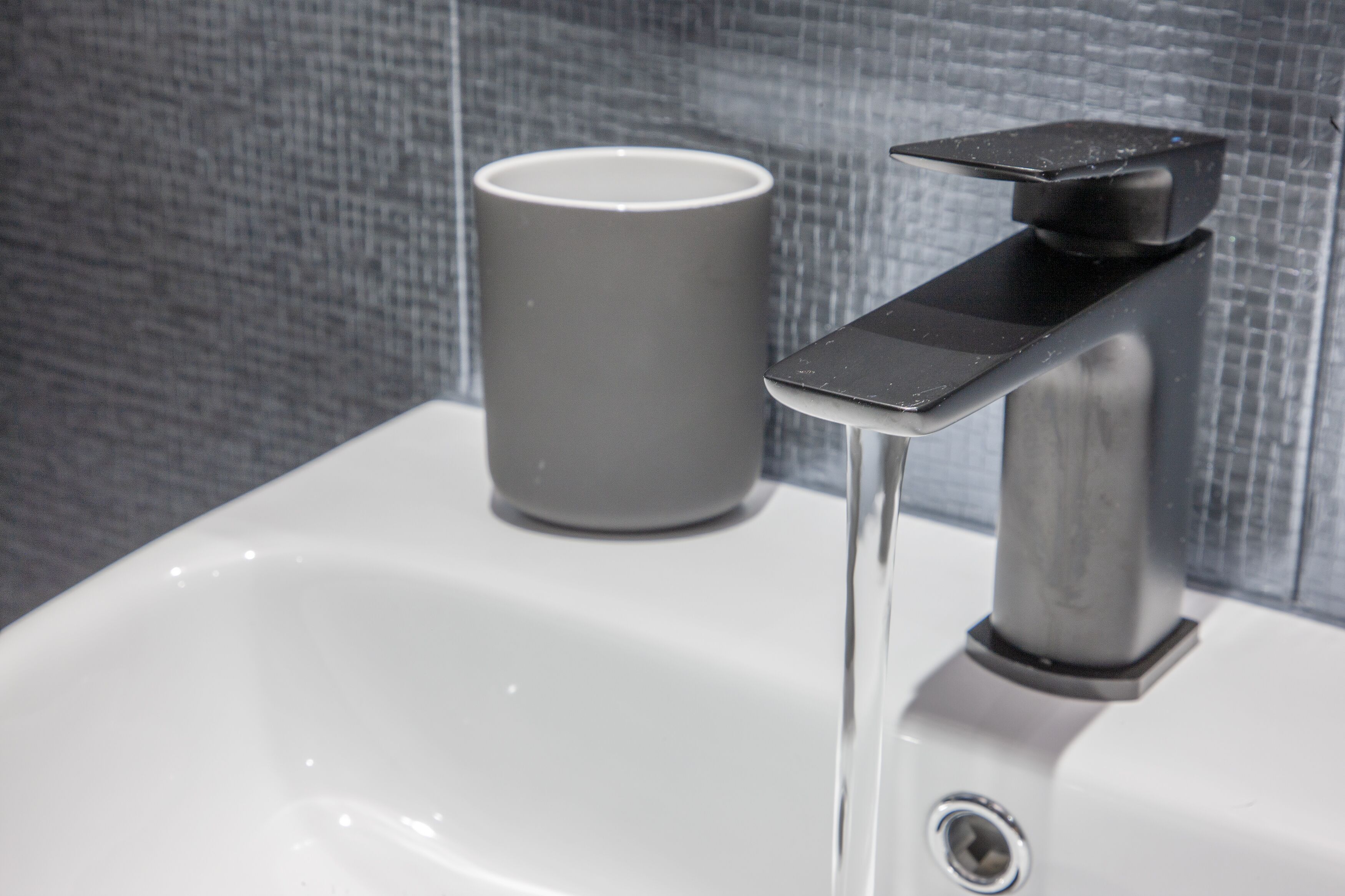 A bathroom sink with a faucet and a cup.