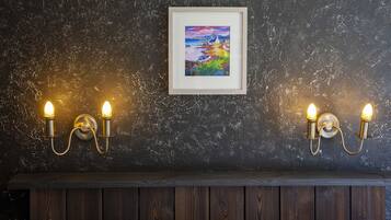 A room with a dark textured wall, a framed painting, and two wall-mounted light fixtures.