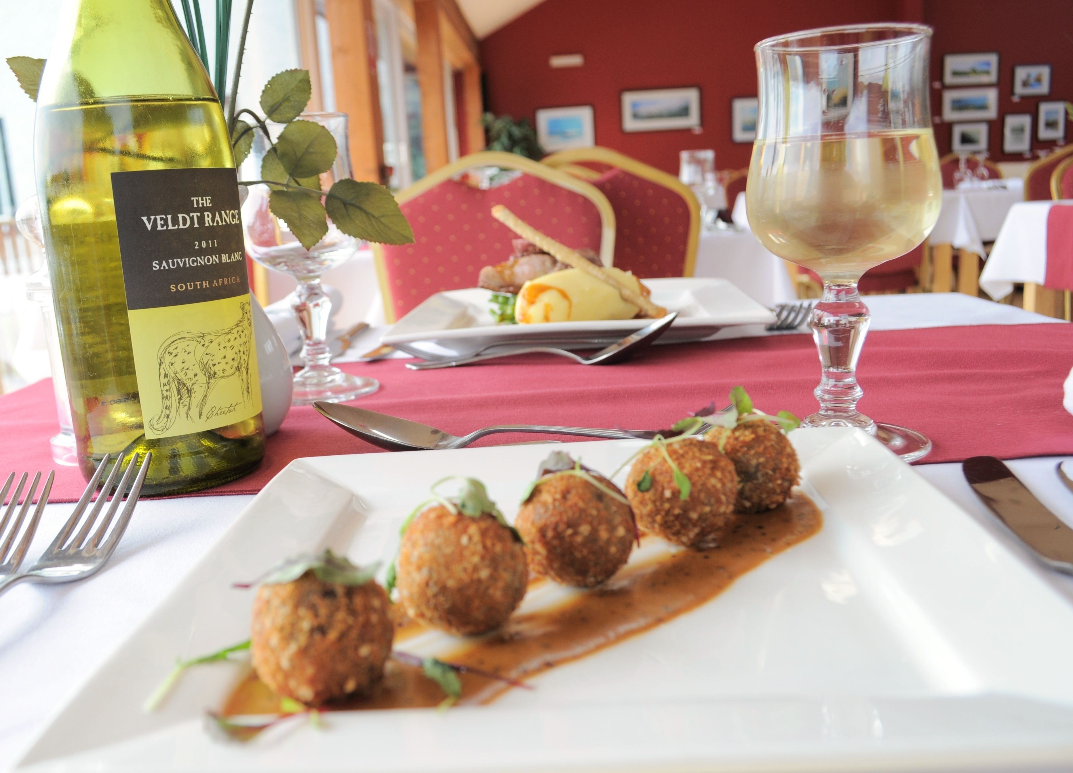Una mesa de comedor con una botella de vino, una copa de vino y un plato de comida.