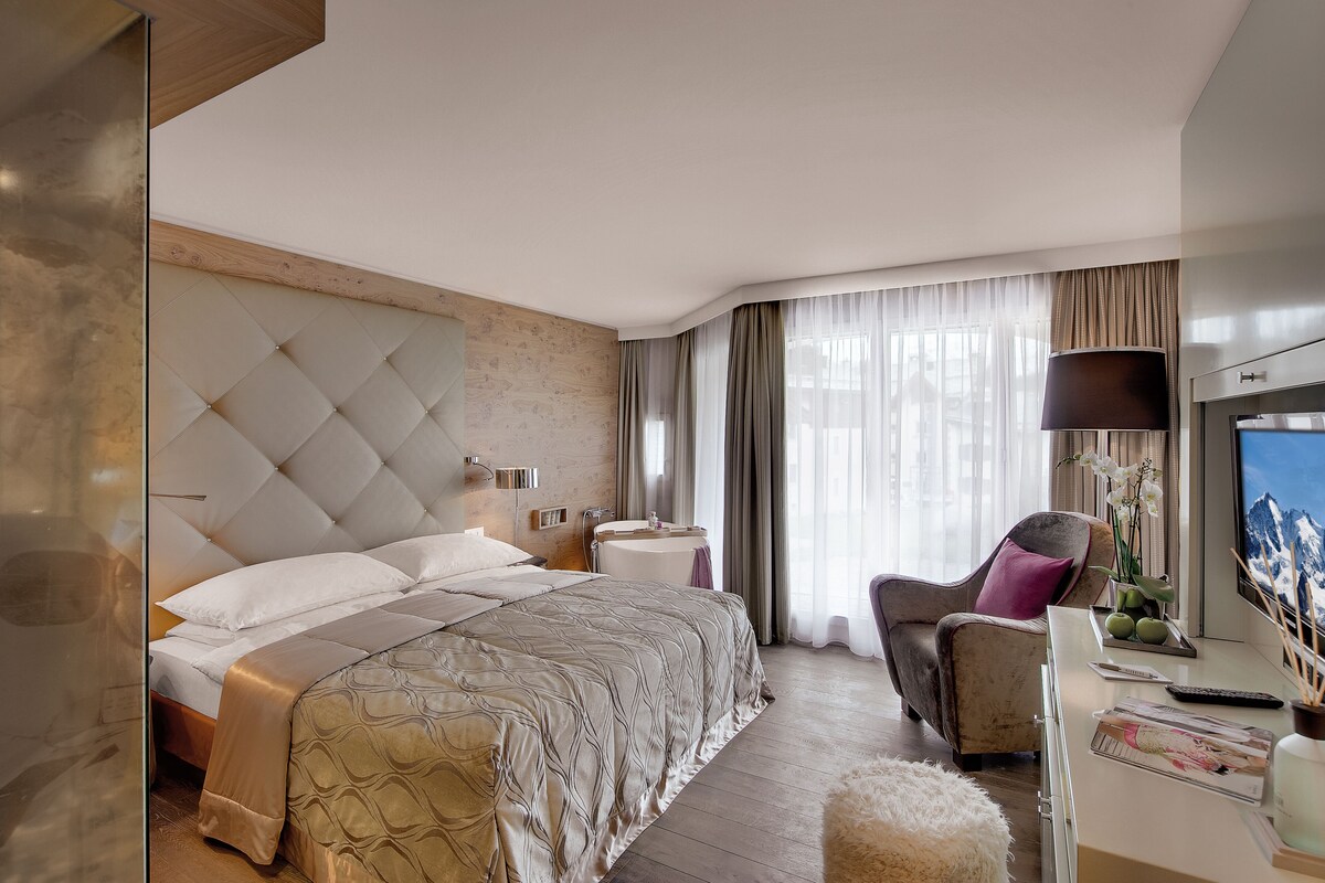 Een moderne hotelkamer met een groot bed, een bureau met een televisie en een raam met gordijnen.