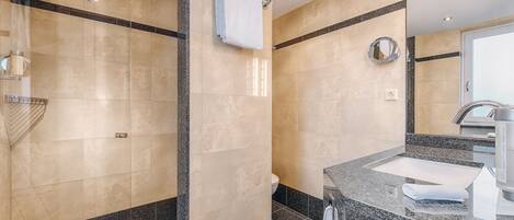 A modern bathroom with a large mirror, a sink, and a shower area.
