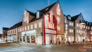 Um hotel com fachada vermelha, várias janelas e uma placa indicando que funciona como hotel, restaurante e bistrô.