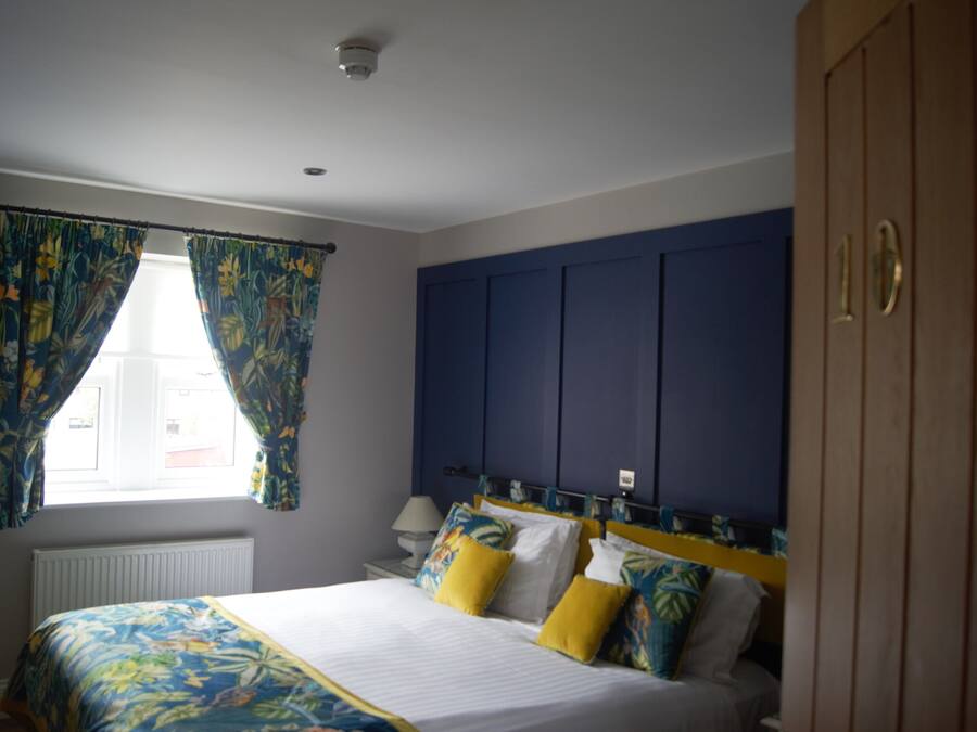A bedroom with a bed, curtains, a nightstand, a lamp, and a wardrobe.