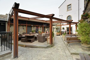 Un área de patio al aire libre con mobiliario de madera y una estructura de pérgola.