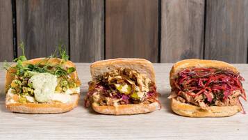 Three sandwiches on a wooden surface.