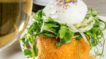 A plated dish with a poached egg, greens, and sauce, accompanied by a bottle of wine.